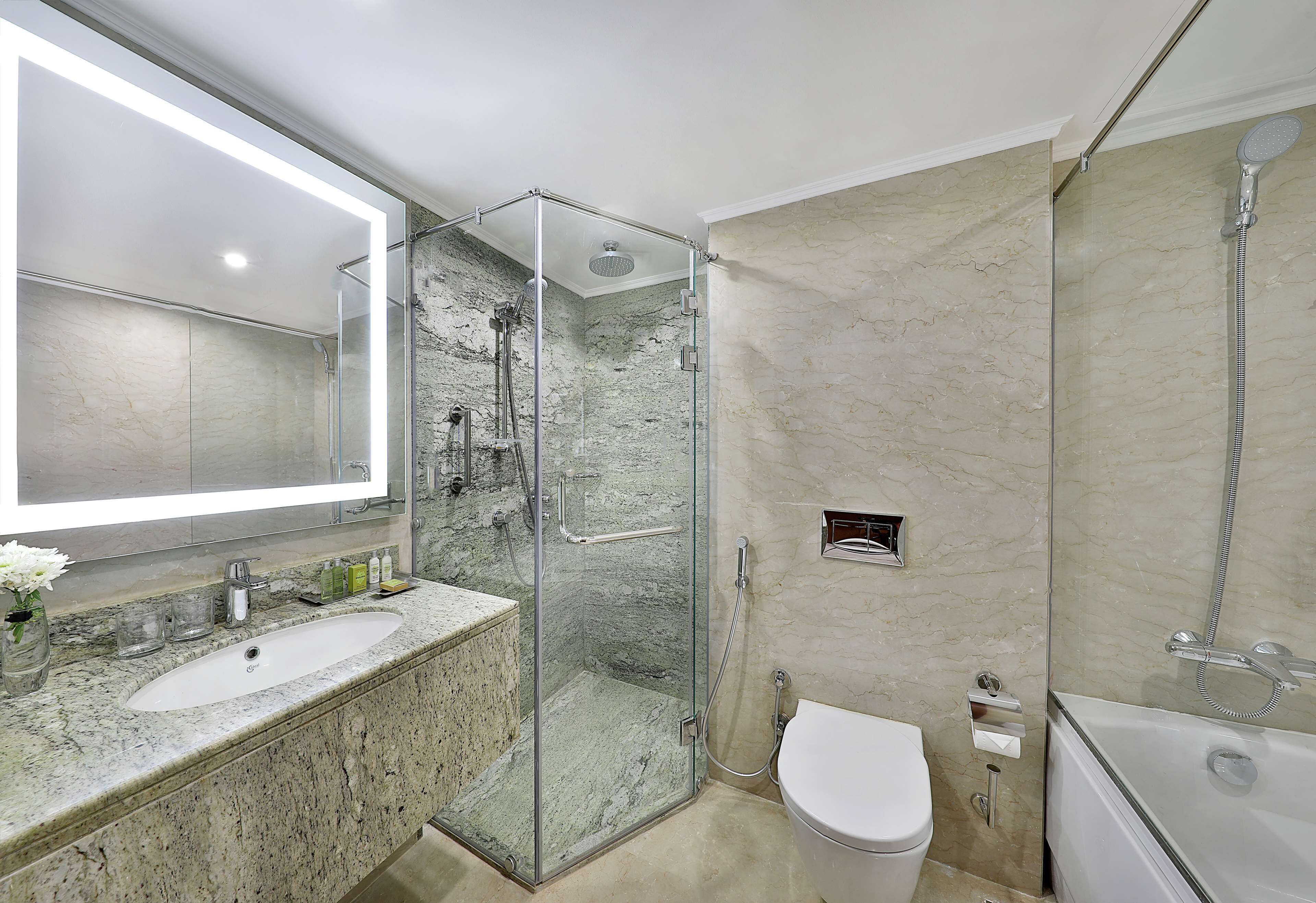 A modern bathroom with a glass-enclosed shower, a standalone toilet, and a bathtub.