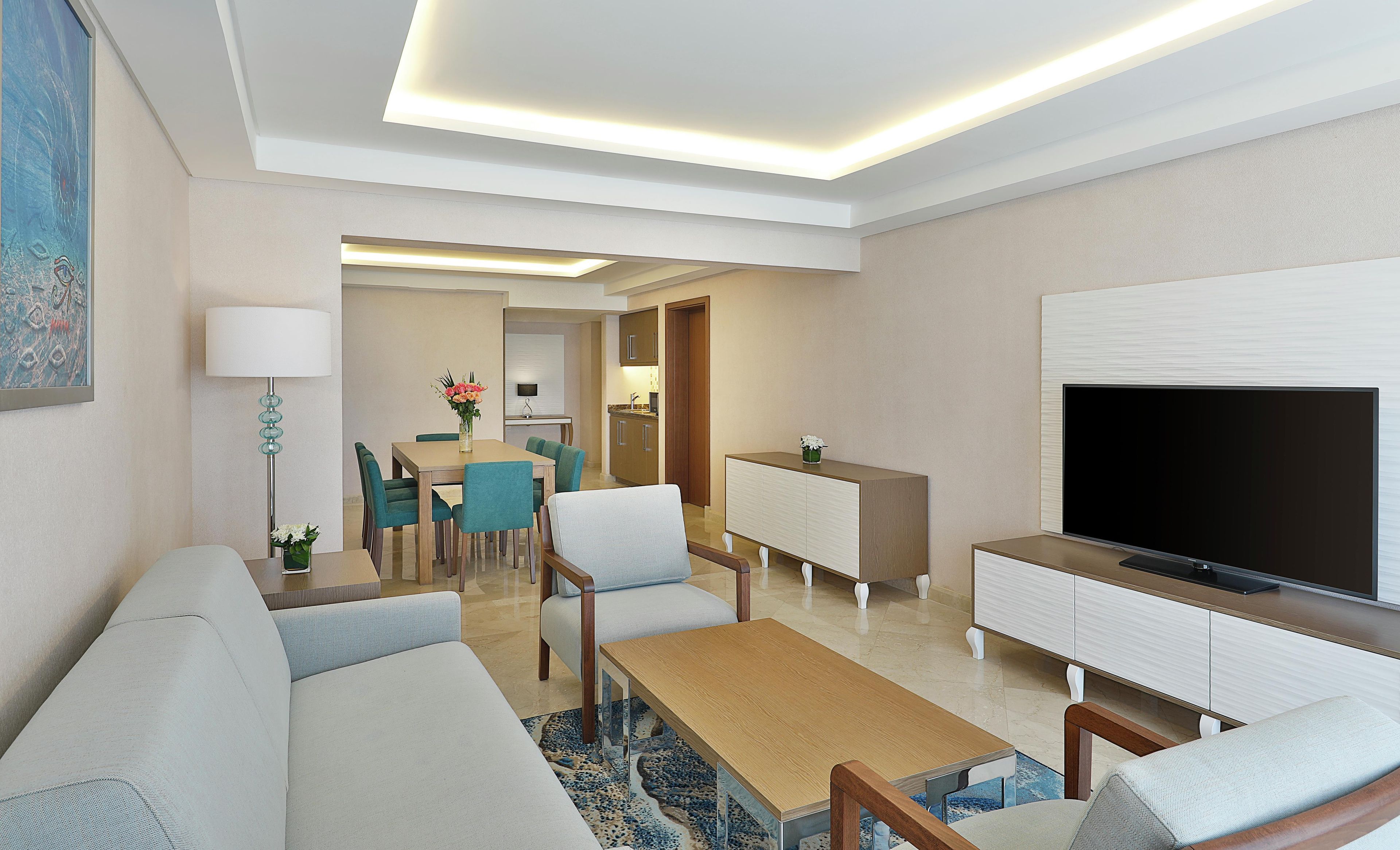 A modern living room with a sofa, coffee table, TV, and a dining area with chairs and a table.