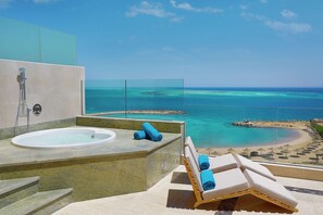 A balcony with a bathtub, lounge chairs, and a view of a beach and ocean. - Hilton Hurghada Plaza (Hurghada)