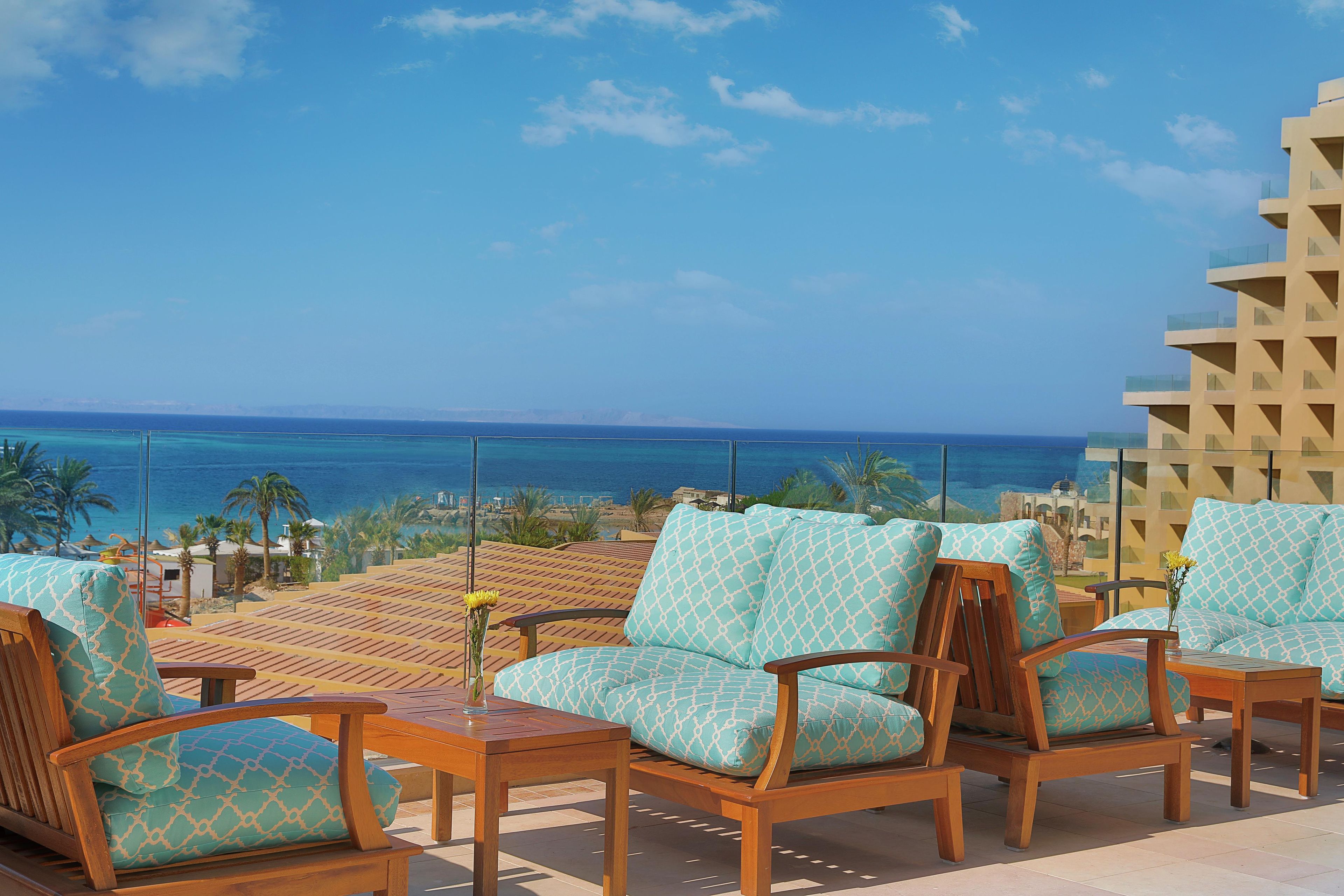 A terrace with wooden furniture and a view of the ocean.