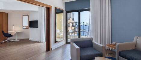 A modern hotel room with a balcony, a seating area, and a dining space.