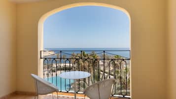 A balcony with a view of a pool and palm trees.
