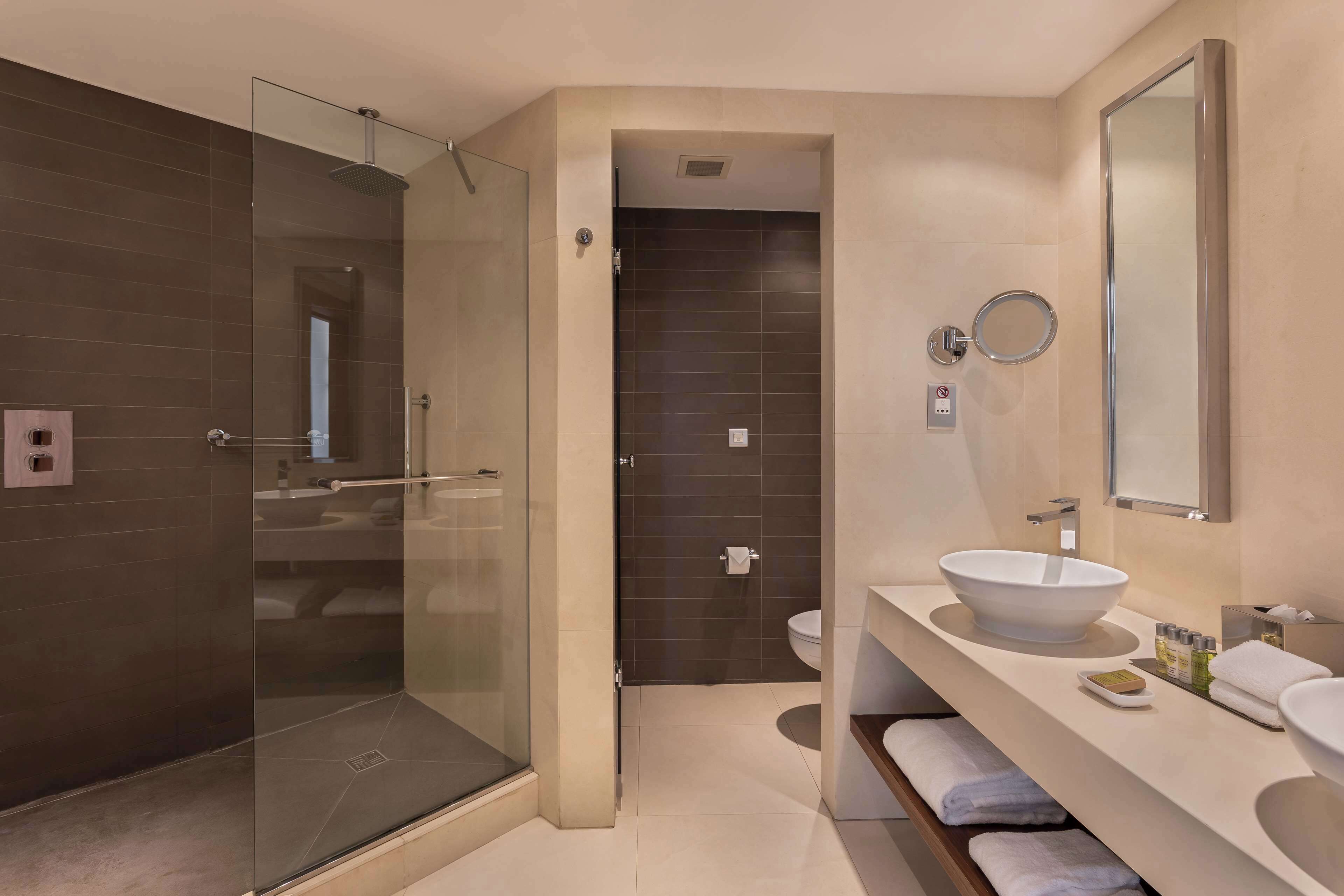 Une salle de bain moderne avec une douche à parois de verre, un grand lavabo et un miroir.