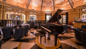 A grand piano in a spacious lobby with a decorative ceiling and seating area. - Hilton Malta (St. Julian's)