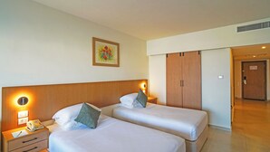 A hotel room with two beds, a nightstand with a phone and lamp, a wooden wardrobe, and a painting on the wall. - Safir Sharm Waterfalls Resort (Sharm El Sheikh)
