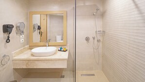A modern bathroom with a glass-enclosed shower, a sink with a mirror, and a hairdryer on the wall.
