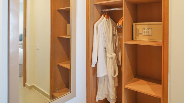 A walk-in closet with a large mirror, wooden shelving, and a safe.