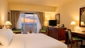 A hotel room with a bed, a desk, a television, and a view of the ocean. - Safir Sharm Waterfalls Resort (Sharm El Sheikh)