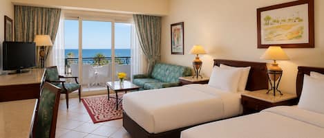 A hotel room with a balcony, a television, a sofa, a bed, and a desk.