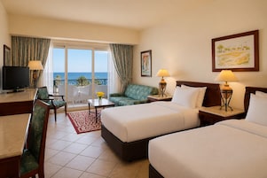 A hotel room with a balcony, a television, a sofa, a bed, and a desk.