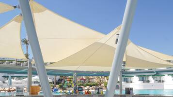 A poolside area with a water slide, lounge chairs, and a pool.