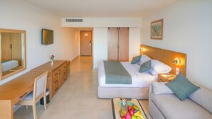 A hotel room with a bed, a sofa, a desk, and a TV.