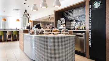 En modern inredning för ett kafé, med en central disk, sittområde och en Starbucks-skylt.