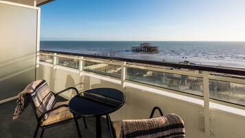 A balcony with a view of the ocean, featuring a small table and two chairs.