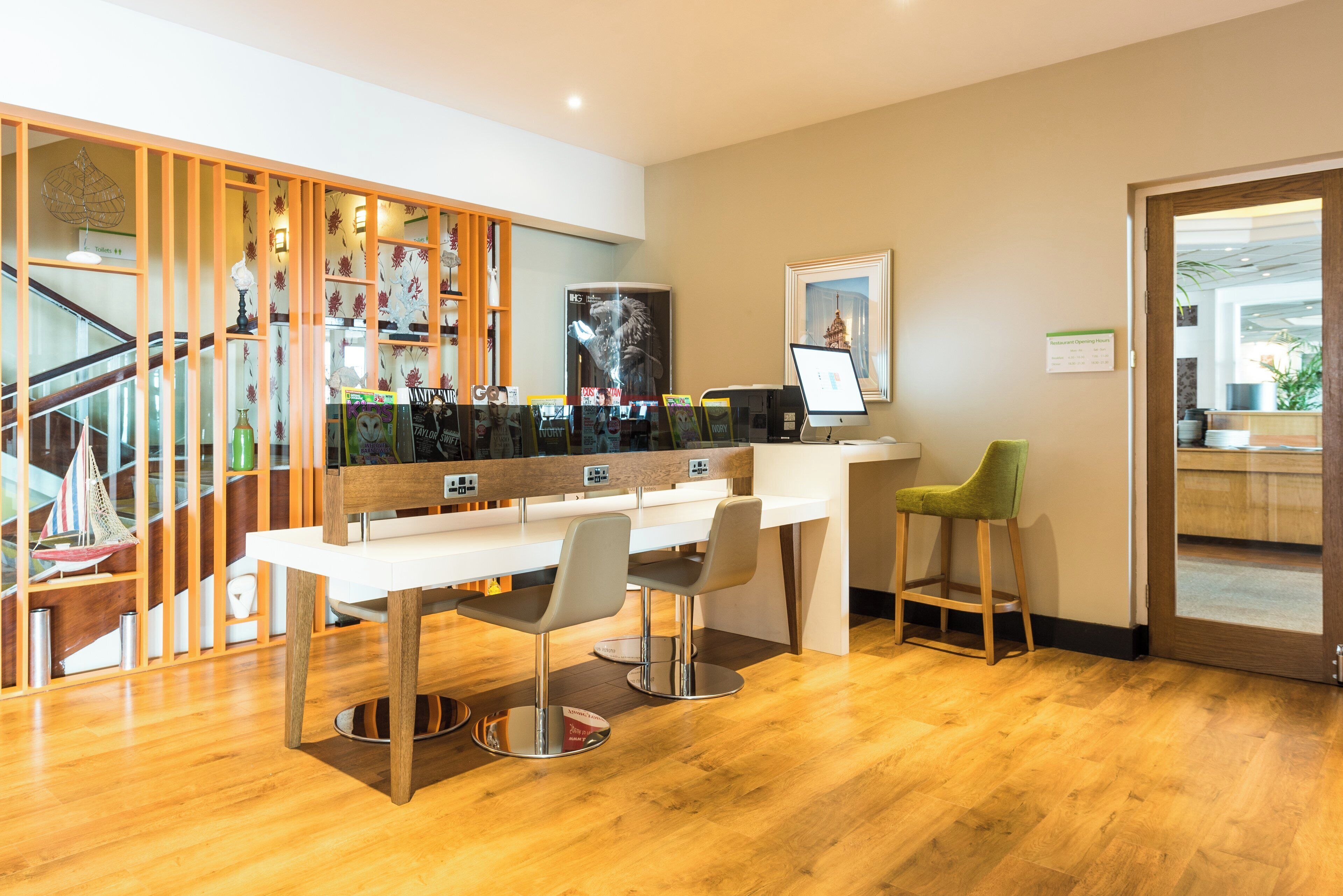 A modern hotel lobby with a reception desk, seating area, and a staircase.
