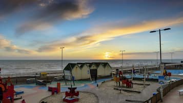 Un parque infantil en la playa con zonas de juego en arena y una estructura de madera.