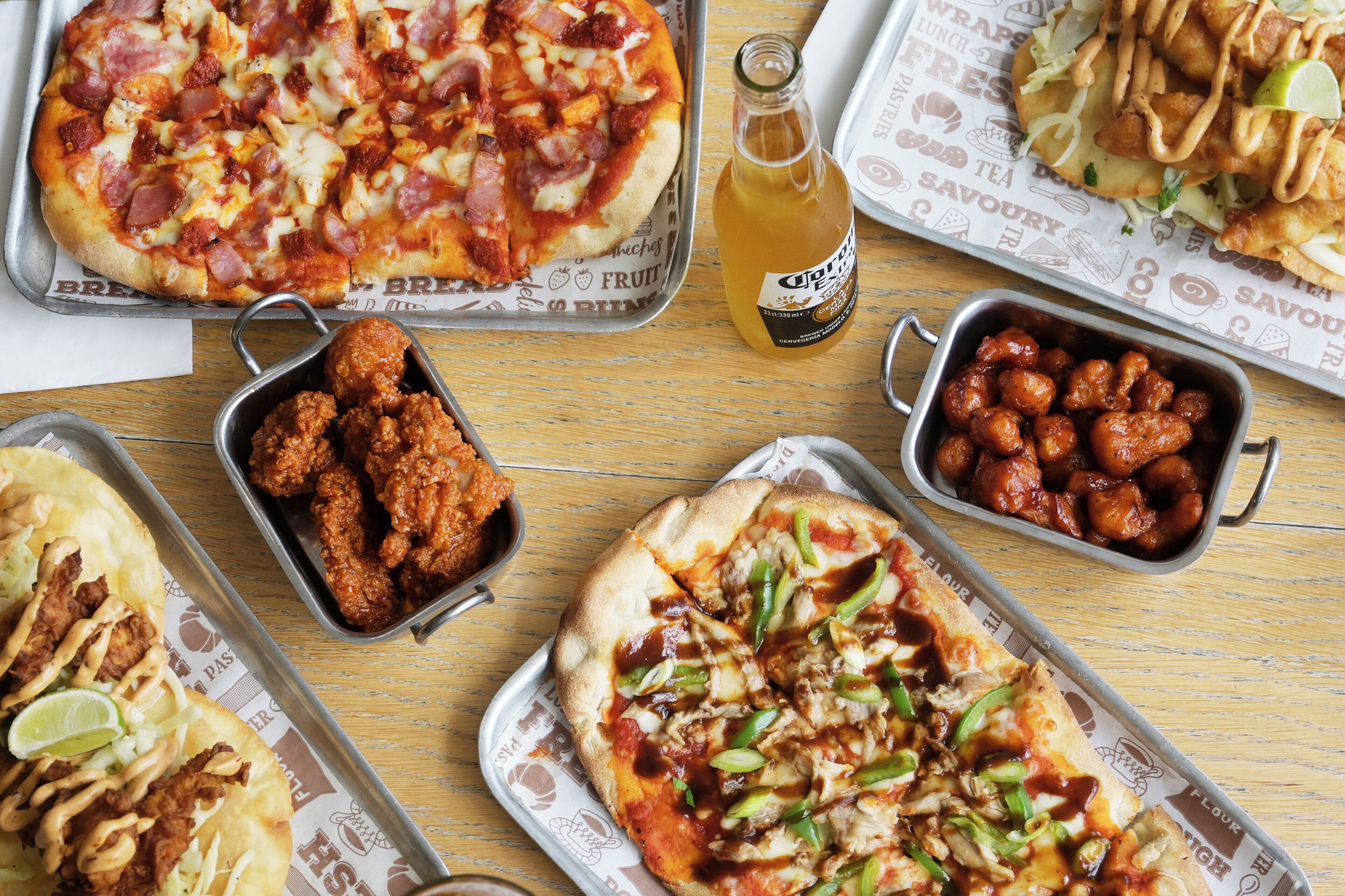 A variety of food items on trays, including pizza, fried chicken, and other dishes.