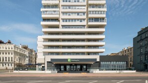 Un hôtel moderne à plusieurs étages, doté d’une façade plate, de balcons à chaque étage et d’une enseigne Holiday Inn bien visible.