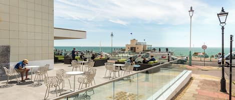 Un espace extérieur aménagé avec des tables et des chaises, offrant une vue sur un plan d’eau.