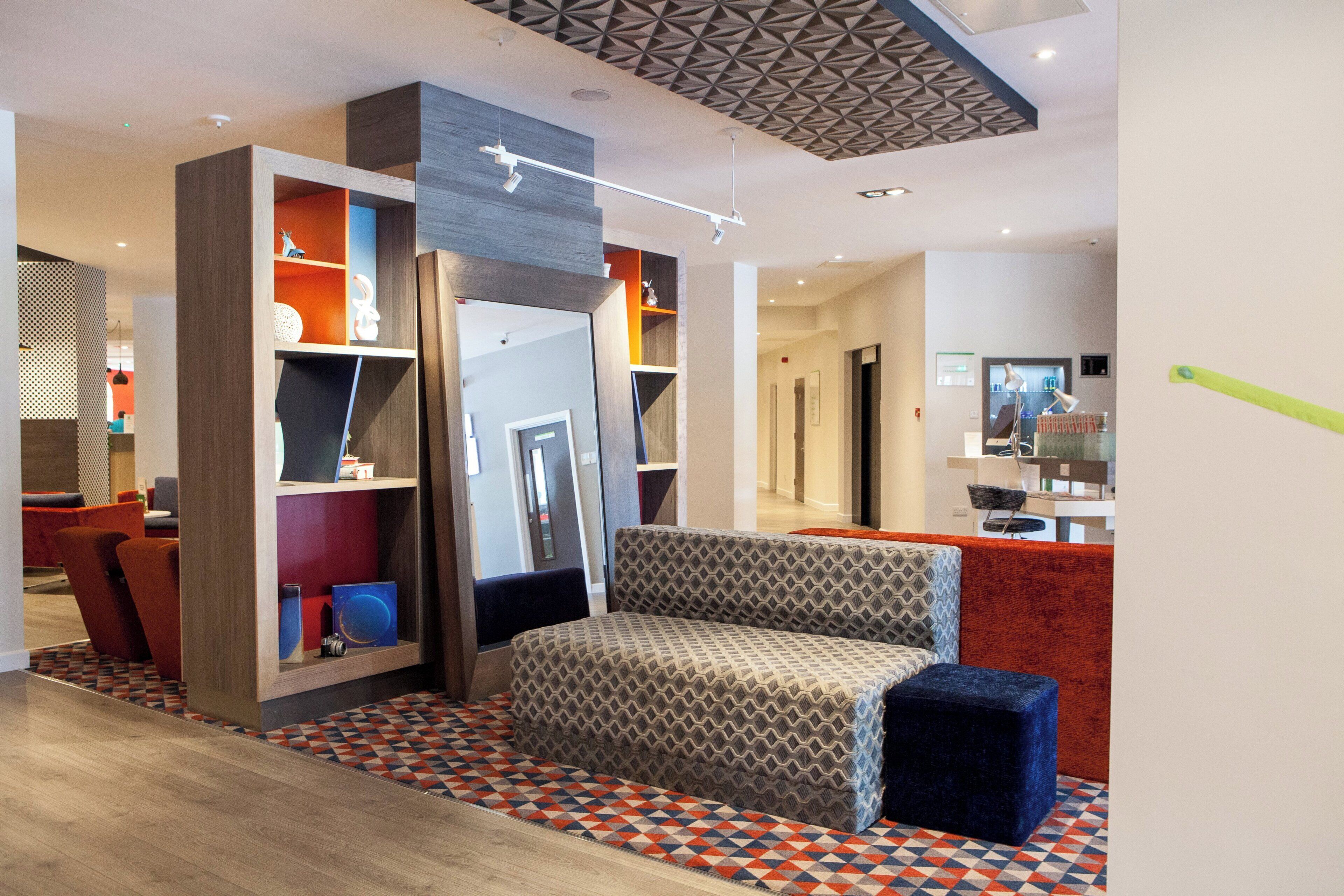A modern interior with a sofa, patterned cushions, and a geometric ceiling design.