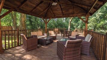 A covered outdoor seating area with wicker furniture and a wooden deck.