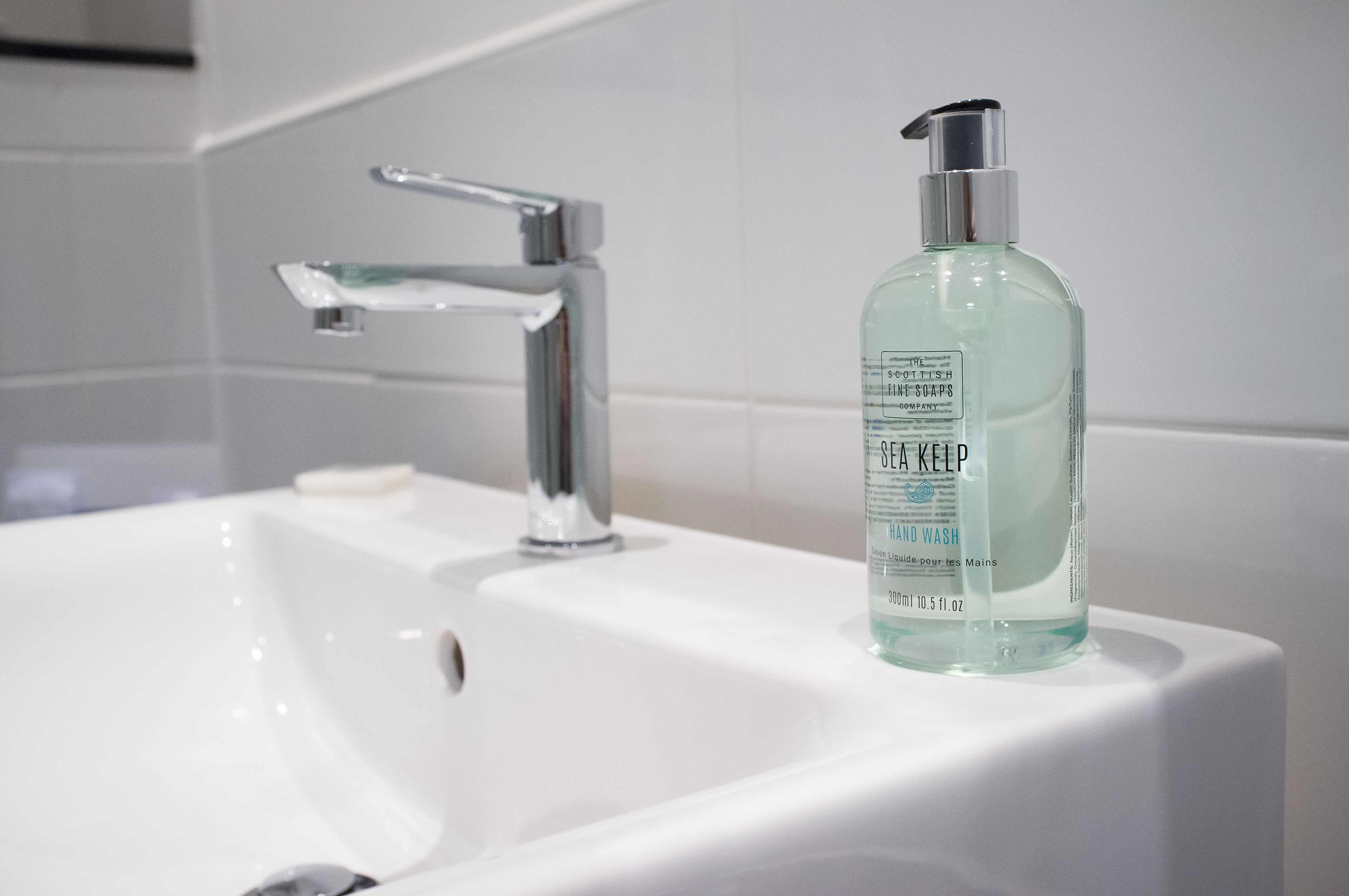 A bathroom sink with a modern faucet and a bottle of soap.