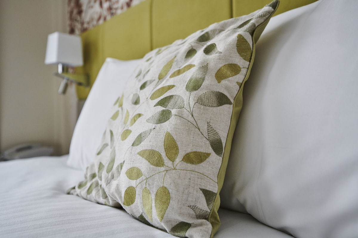 A bed with a pillow featuring a leaf pattern.
