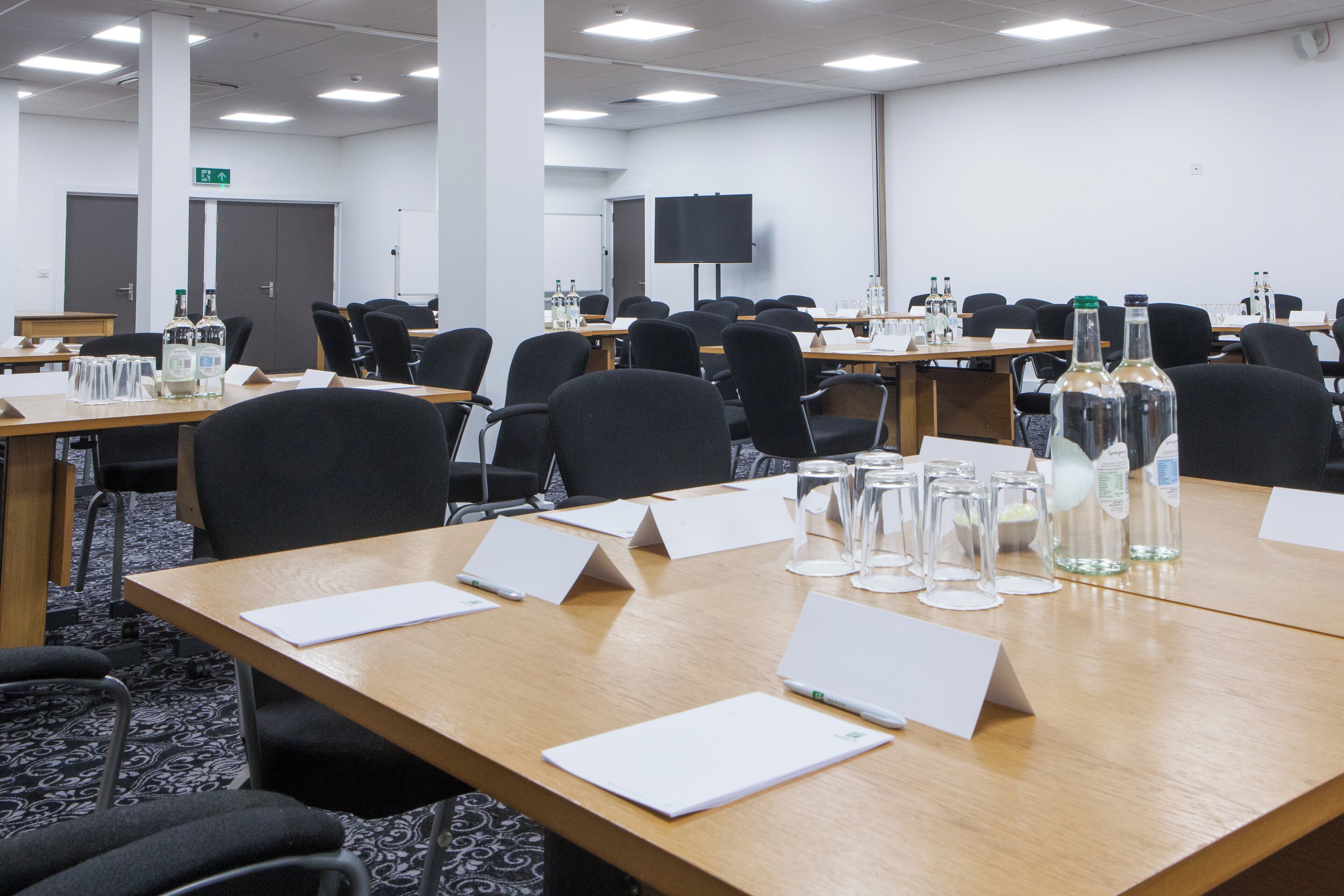 A conference room with tables, chairs, and presentation screens.