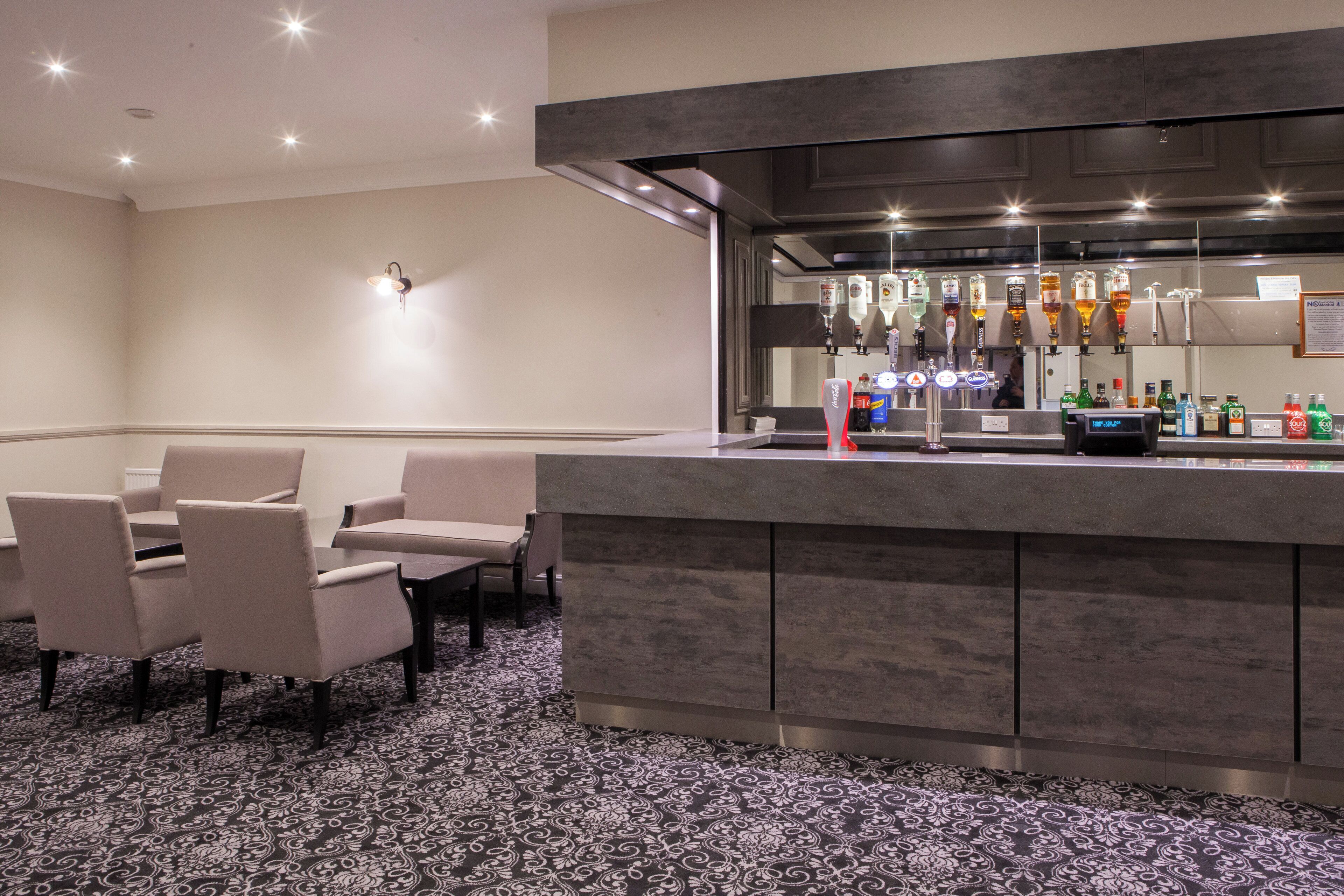 A bar area with a counter, seating, and a variety of bottles.