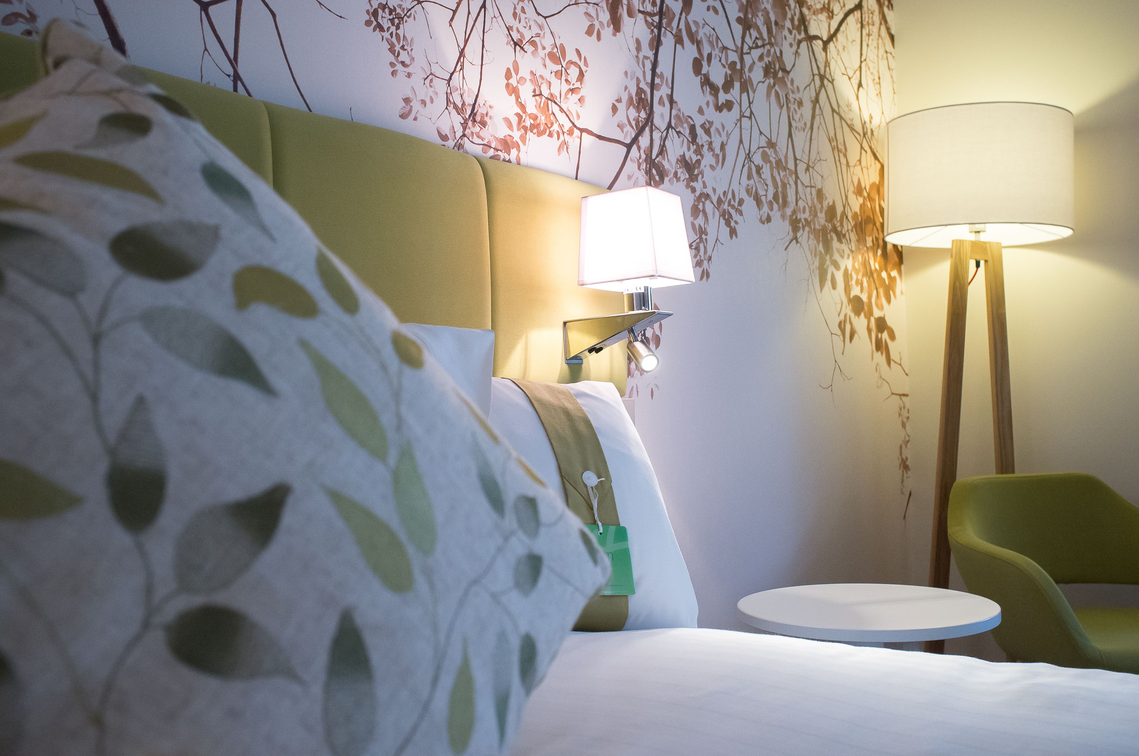 Une chambre d’hôtel avec un lit, une table de chevet, une lampe et une chaise.