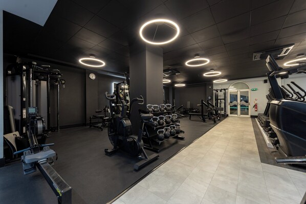 A gym with exercise equipment, a weight rack, and a treadmill. - Holiday Inn Corby Kettering Hotel & Spa (Corby)