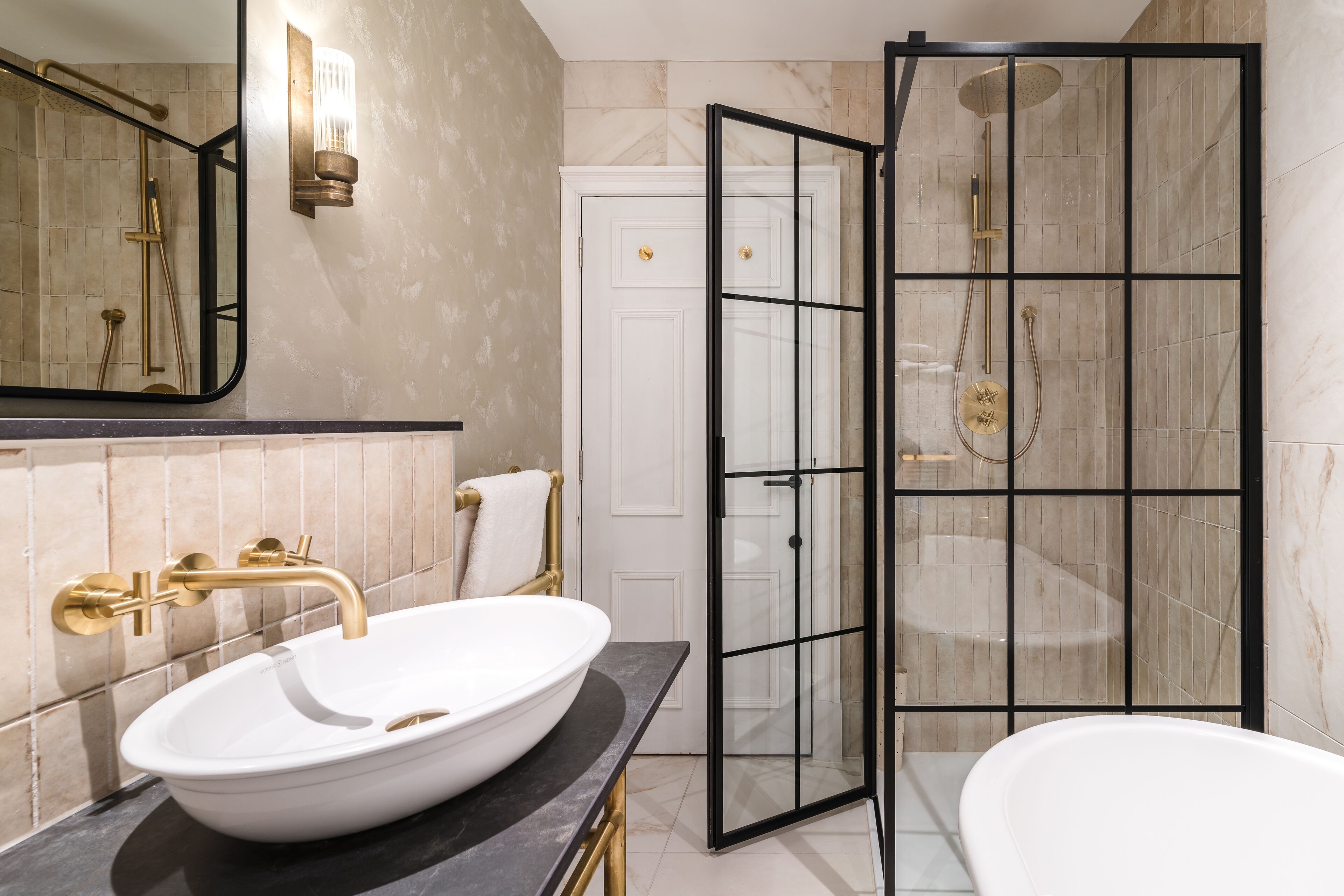 Un baño con un lavamanos grande de color blanco, una ducha con cerramiento de vidrio y una bañera blanca.