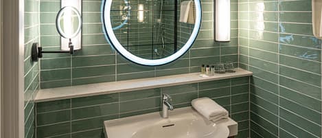 Un baño con un espejo redondo, un lavabo y un perchero para toallas.