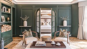 A room with a bed, two armchairs, a coffee table, and a bookshelf. - Dunkeld House Hotel (Dunkeld)