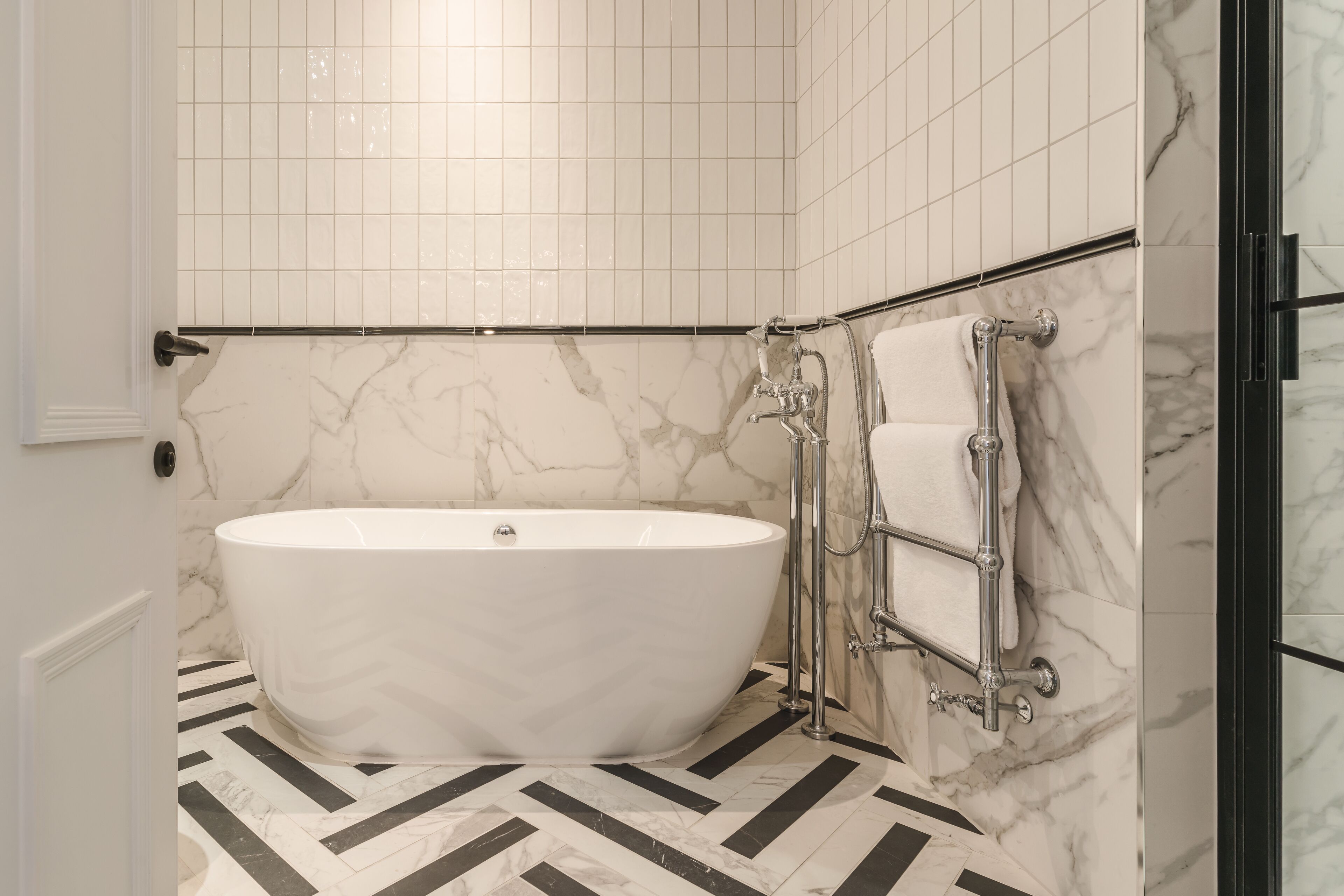 Un baño con una bañera independiente, un perchero para toallas y una zona de ducha.