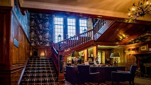 A grand lobby with a staircase, wooden paneling, and a chandelier. - Dunkeld House Hotel (Dunkeld)