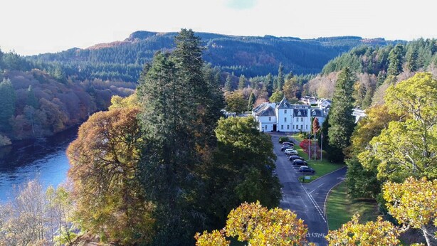 A large white building with a driveway and parked cars, surrounded by trees and hills. - Dunkeld House Hotel (Dunkeld)