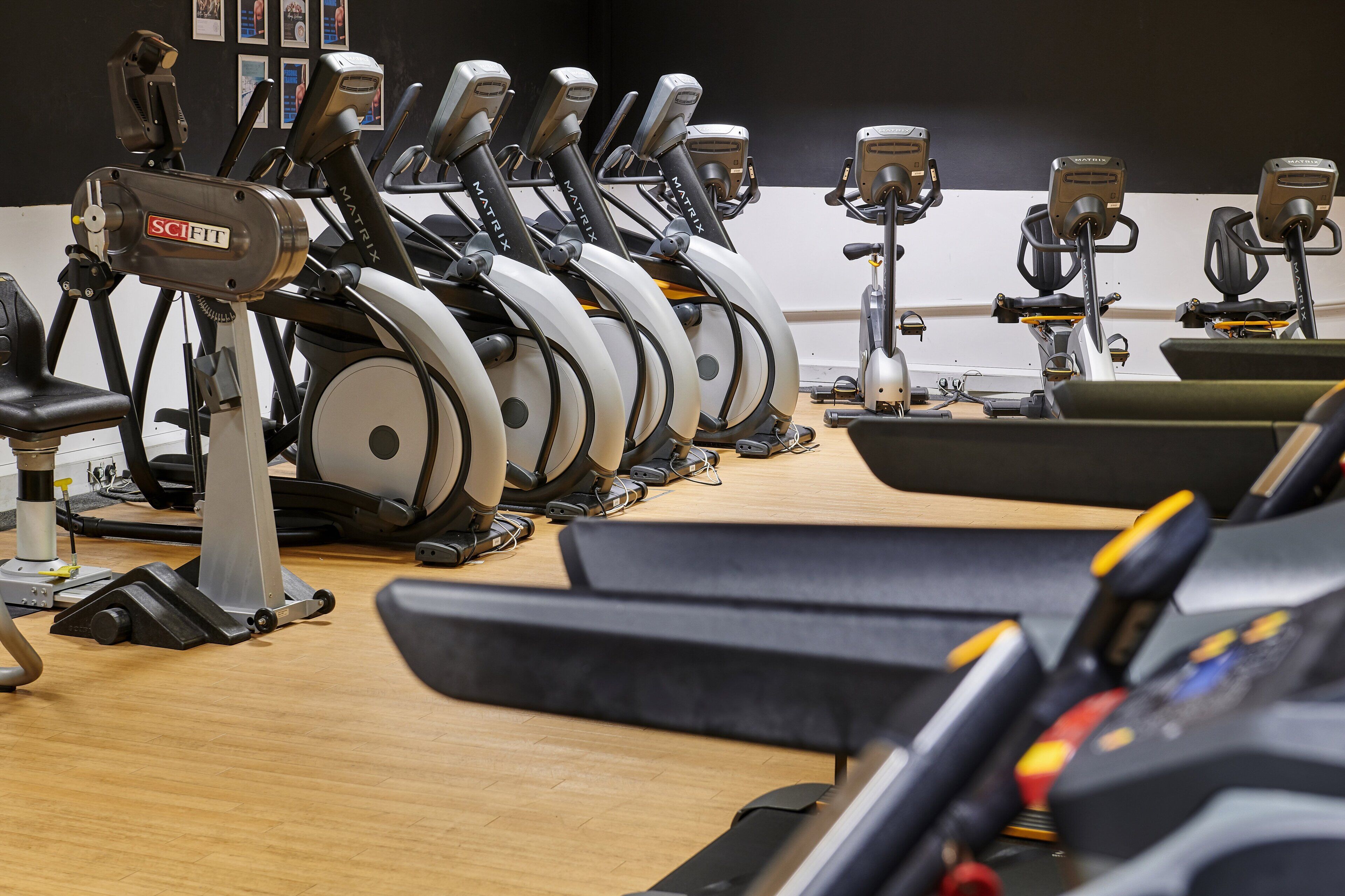 Un gimnasio con varias bicicletas estáticas y cintas de correr.