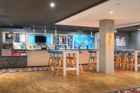 A modern bar area with wooden stools, a bar counter, and a blue-tiled wall with artwork. - Holiday Inn Glasgow East Kilbride by IHG (Glasgow)