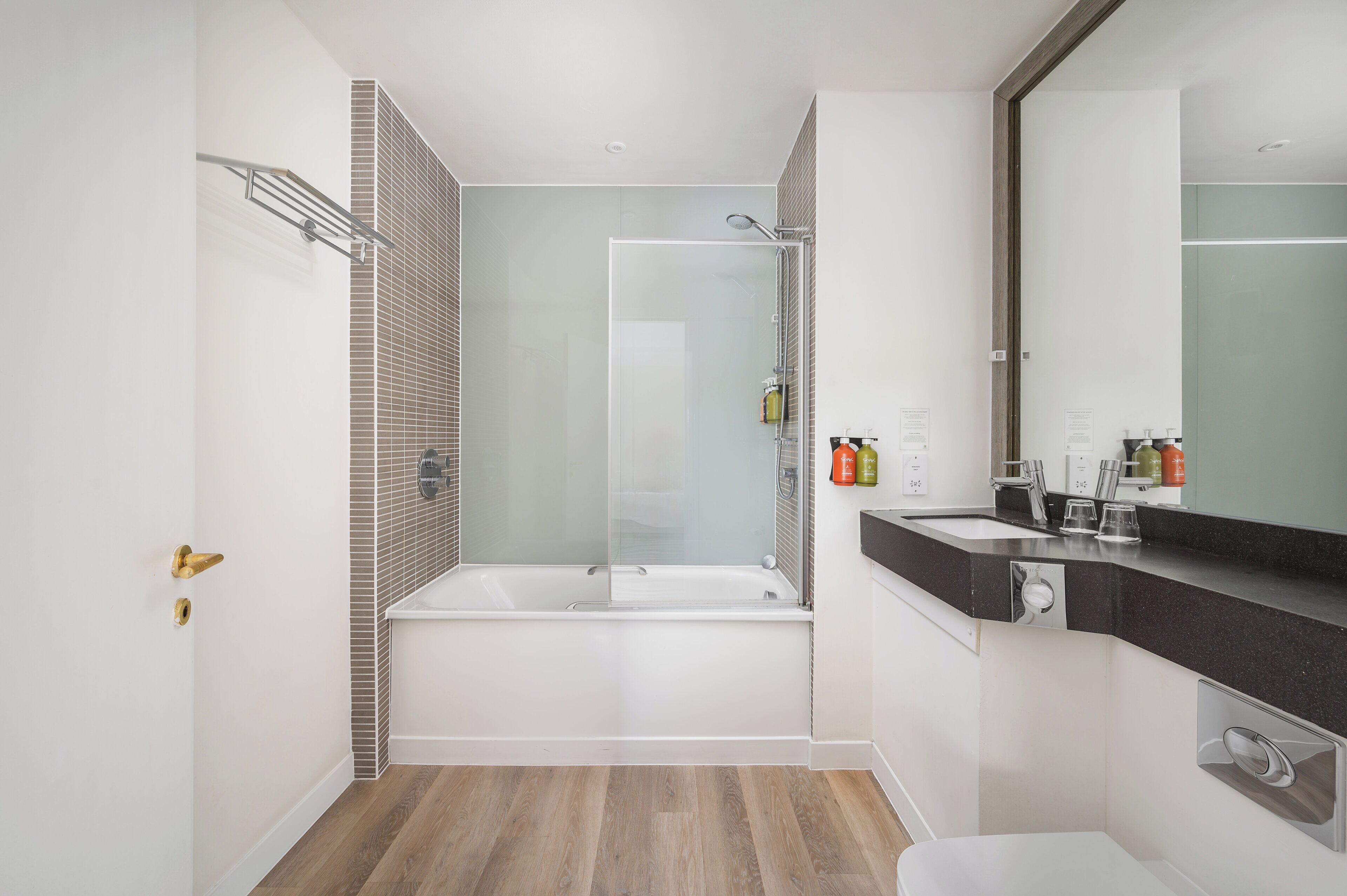 Une salle de bain moderne dotée d’une douche à parois de verre, d’une baignoire sur pieds et d’un meuble-lavabo avec un grand miroir.