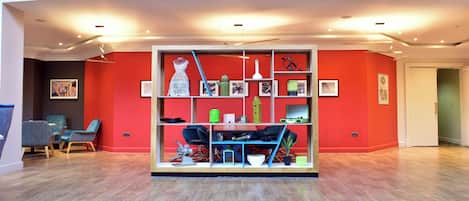 A modern living room with a red accent wall, a built-in bookshelf, and a seating area with two chairs.