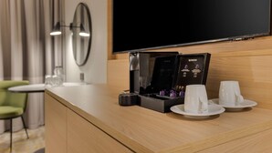 A hotel room with a wooden counter, a coffee machine, two white cups, and a flat-screen TV. - DoubleTree by Hilton Edinburgh Airport (Newbridge)