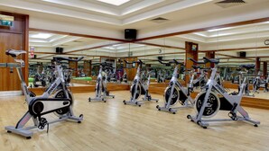 A gym with multiple stationary bikes, wooden floors, and mirrors on the walls. - DoubleTree by Hilton Edinburgh Airport (Newbridge)