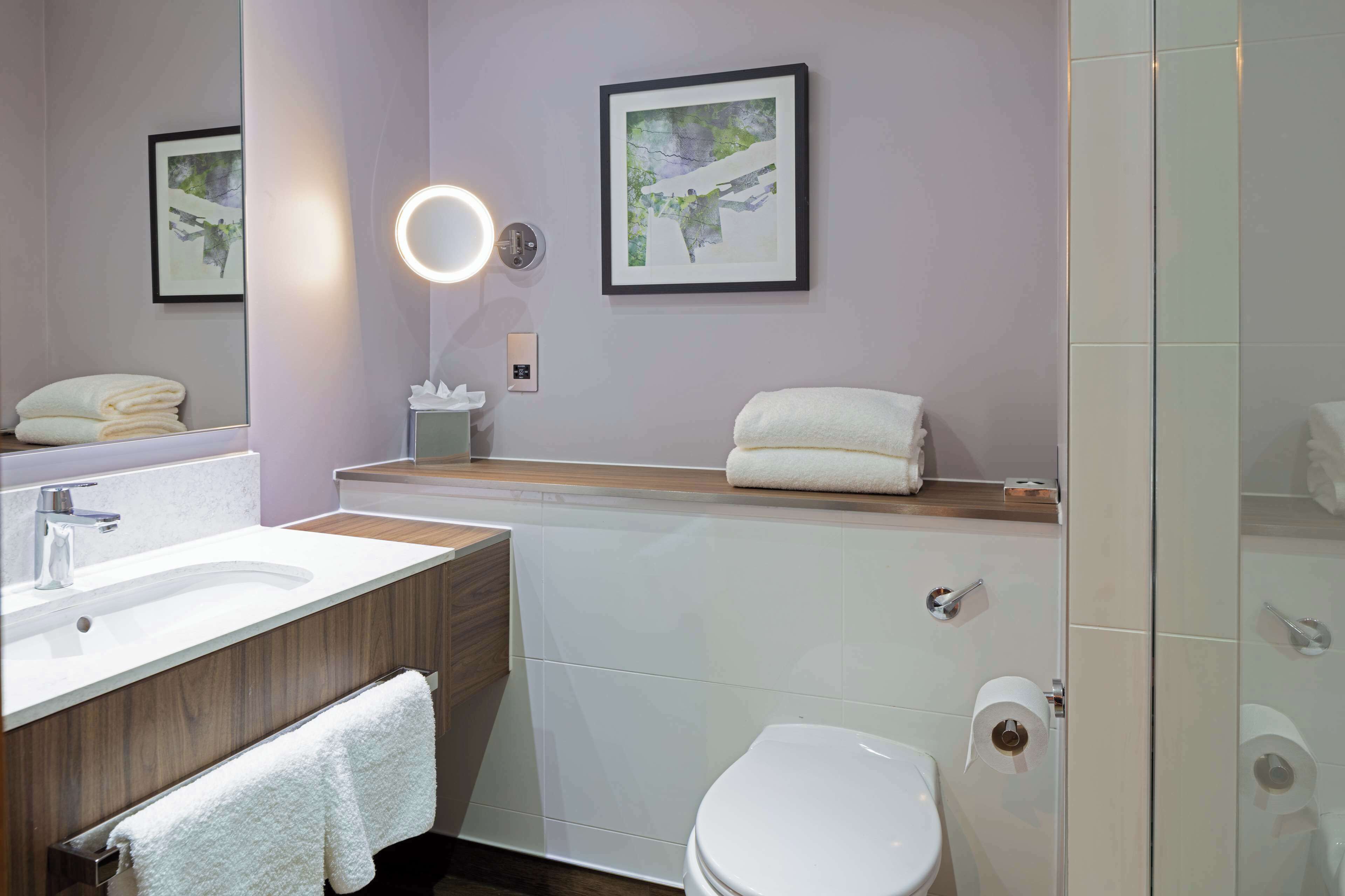 A modern bathroom with a vanity, sink, mirror, and toilet.
