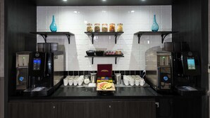 A coffee station with two espresso machines, a display of coffee pods, and a variety of jars on shelves. - DoubleTree by Hilton Edinburgh Airport (Newbridge)