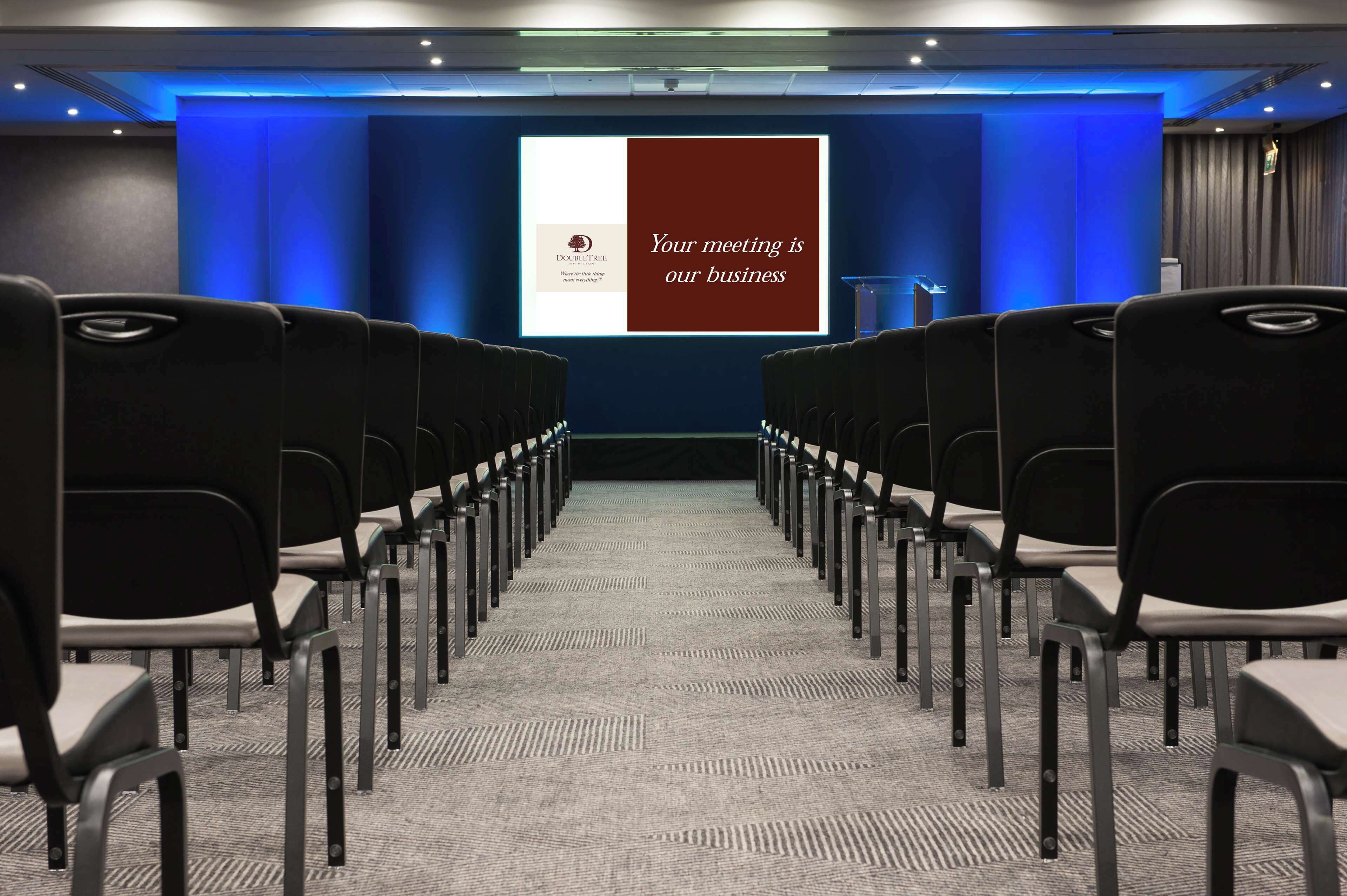 Ett konferensrum med rader av stolar vända mot en presentationsskärm.