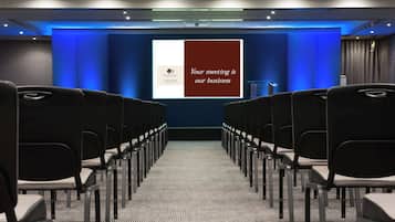 A conference room with rows of chairs facing a presentation screen.