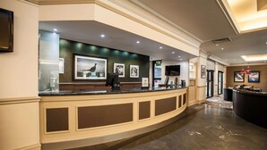 A hotel reception area with a curved counter, framed pictures on the wall, and a marble floor. - DoubleTree by Hilton Edinburgh Airport (Newbridge)