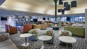 A spacious lobby with multiple seating areas, a fireplace, and a bar area with shelves of items. - ORIDA Hotels Newbury (Newbury)