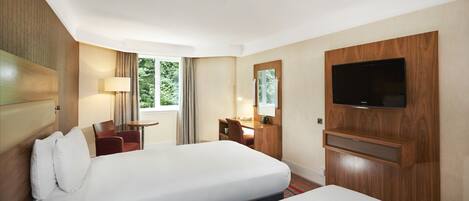 A hotel room with two beds, a desk, a chair, a TV, and a window with curtains.